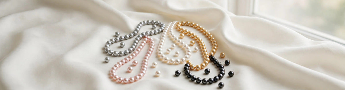 Freshwater pearl necklaces in natural grey, pink, white, gold and black pearl colours arranged on ivory silk