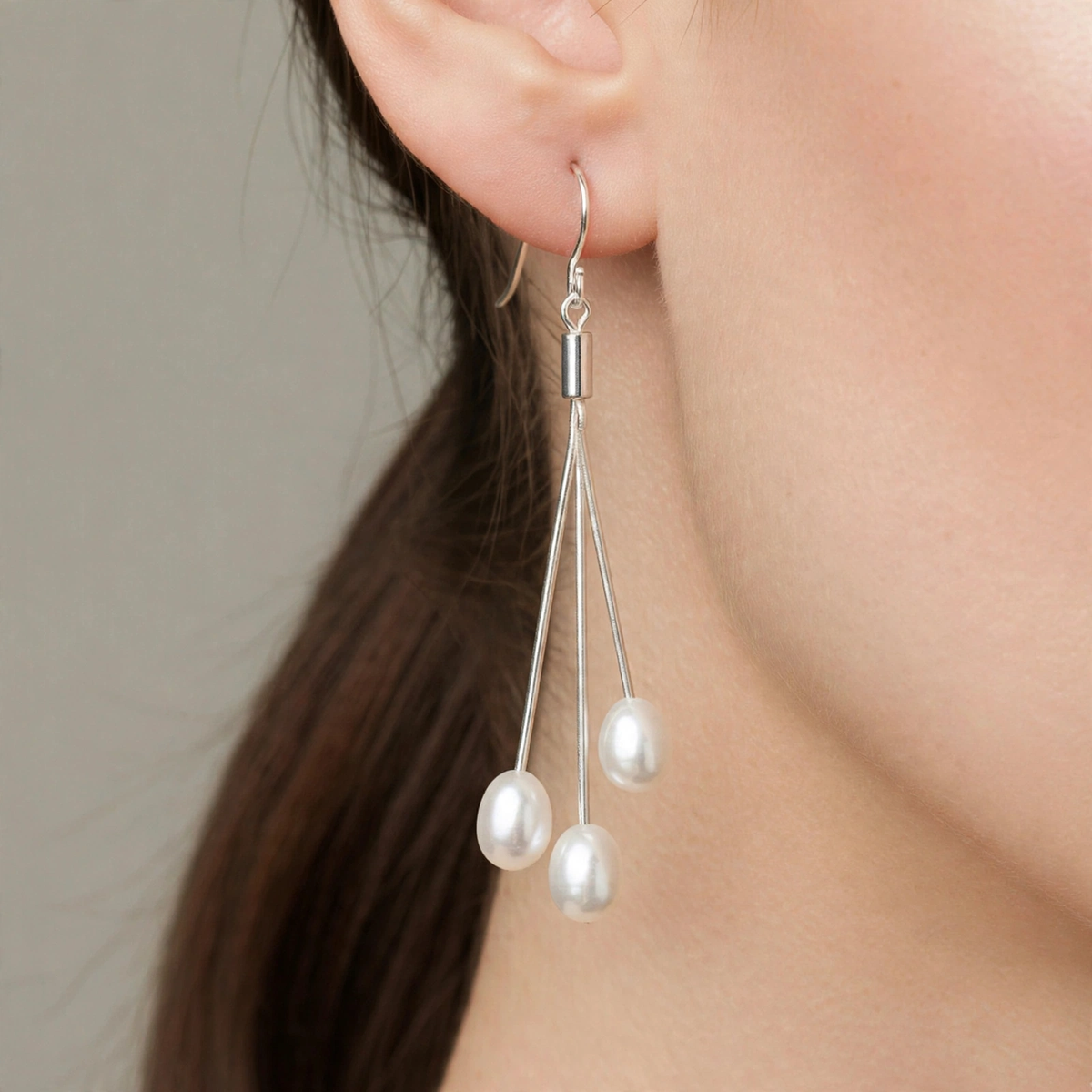 White trilogie freshwater pearl drop earring worn on ear, close-up — Golden Rose Arts